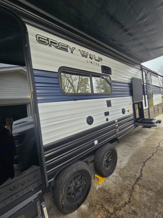 Grey Wolf Limited travel trailer side, ideal for an RV rental. Features blue/white exterior, outdoor kitchen, and extended awning.. Forest River Cherokee Grey Wolf 2024