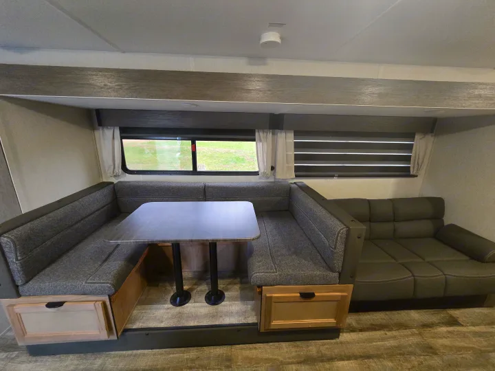 Cozy RV rental dinette with L-shaped bench seating, table, and storage drawers, plus a comfy sofa. Ideal for travel!. Forest River Cherokee Grey Wolf 2024