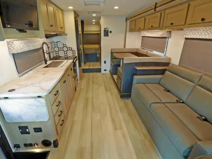 Spacious rv rental interior featuring a full kitchen, comfortable dinette, sofa seating, and bunk beds for family travel.. Classe C C31 pieds avec extension(s) 2023
