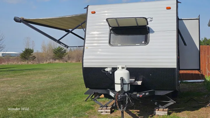 An RV rental travel trailer is set up outdoors with its awning extended and window open, ready for adventure.. Forest River Viking 2018