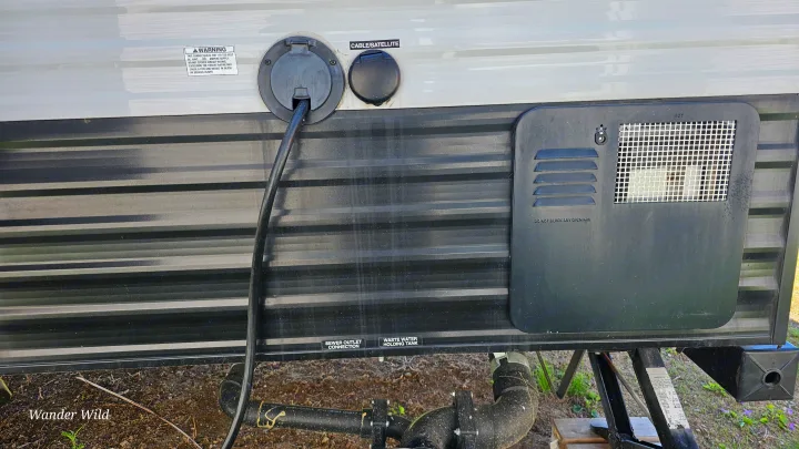 An rv rental's exterior utility panel, featuring power, cable, water heater access, and waste connections for full hookup.. Forest River Viking 2018