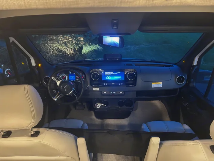 Modern RV rental cockpit at night: sleek dashboard, digital displays, steering wheel, and comfortable front seats.. Thor Delano 2026