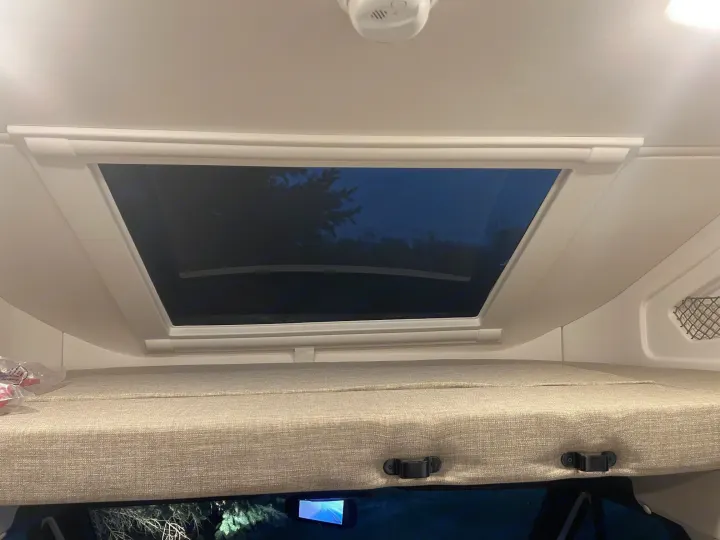 Cozy overhead bunk and skylight in an rv rental, offering a peaceful night view of trees and sky. Ideal for sleeping under the stars.. Thor Delano 2026