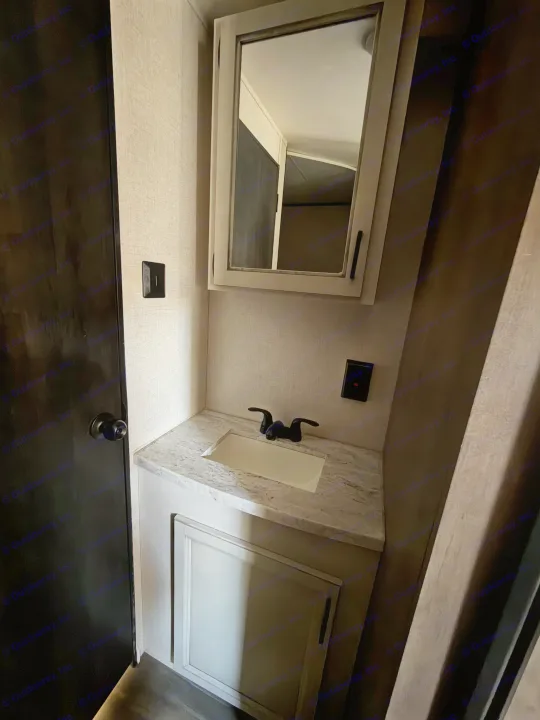Inside an **RV rental**: a compact bathroom with a sink, black faucet, and mirrored cabinet over a marble-look vanity.. Starcraft Autumn Ridge 2022