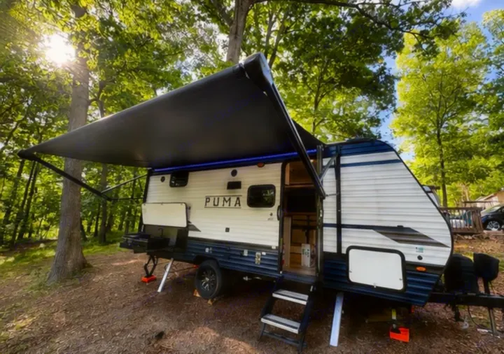 Experience nature with this PUMA rv rental, set up at a wooded campsite with awning and outdoor kitchen.. Puma Palomino 2024