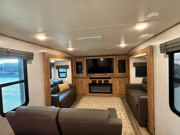 Modern RV rental living area featuring comfortable sofas, a TV, and a fireplace. Enjoy a cozy interior for travel.. Heartland RVs Milestone 2023