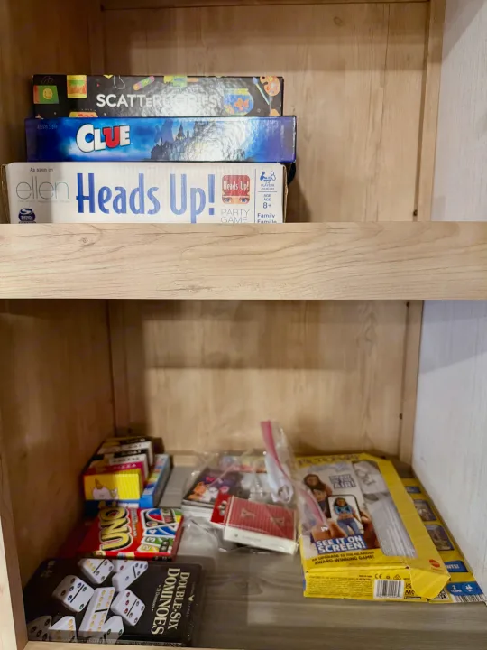 RV rental: A stocked cabinet of board and card games, including Clue, Heads Up!, Uno, and Dominos, ready for family fun.. Heartland RVs Milestone 2023