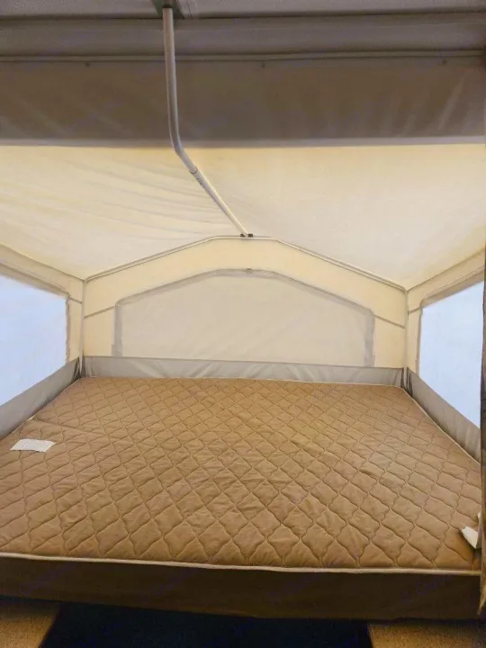 This RV rental offers a comfortable pop-up camper sleeping area with a large, quilted brown mattress.. Forest River Rockwood Freedom 2009