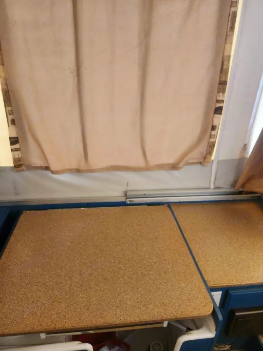 RV rental pop-up camper kitchen: cork-look counters beneath a beige curtain showing wear and stains.. Forest River Rockwood Freedom 2009