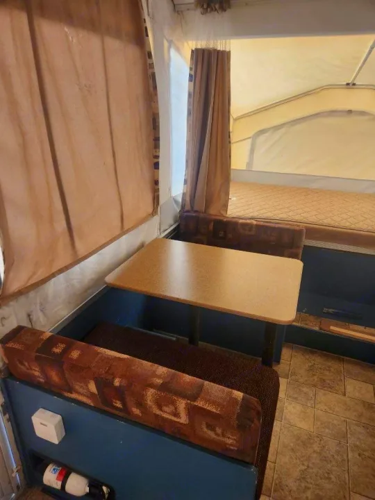 RV rental: Inside this pop-up camper, a dinette with patterned cushions, table, and bed awaits your next adventure.. Forest River Rockwood Freedom 2009