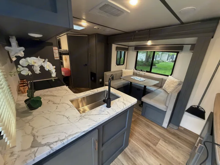 Inside a stylish rv rental: modern kitchen with marble-look counters, sink, and a cozy dinette perfect for travel.. Keystone RV Bullet Crossfire 2022