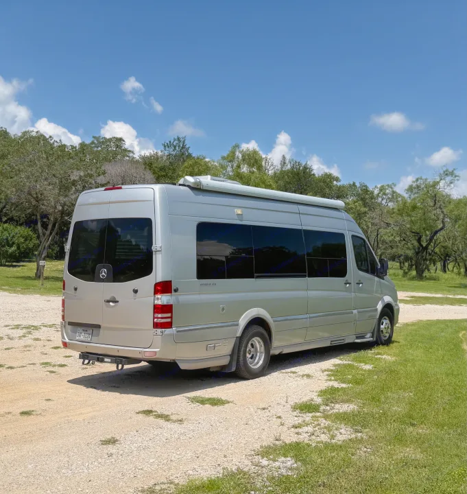 Silver Airstream Interstate camper van, great for rv rental trips. Parked on gravel, ready for adventure under a blue sky.. Airstream Interstate 2014