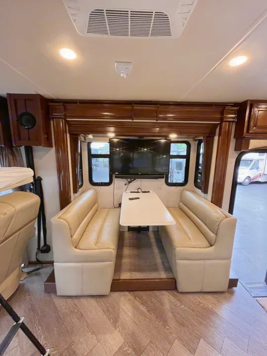 RV rental dinette with cozy benches, table, and TV, perfect for meals and entertainment on the go.. Fleetwood Pace Arrow 2020
