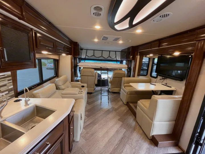 Bright rv rental living space featuring a modern kitchen, cozy recliners, dinette, and a unique overhead bunk bed.. Fleetwood Pace Arrow 2020
