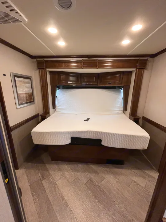 This RV rental features a comfortable bedroom with a white, adjustable mattress, elegant wood cabinetry, and recessed lighting.. Fleetwood Pace Arrow 2020