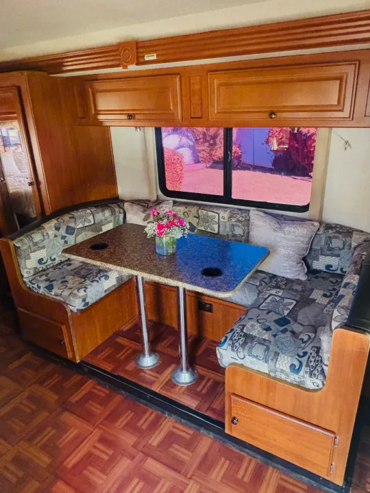 This RV rental features a bright dinette area with patterned booth seating, a granite-look table, and wooden cabinetry.. Jamboree Sport 2011