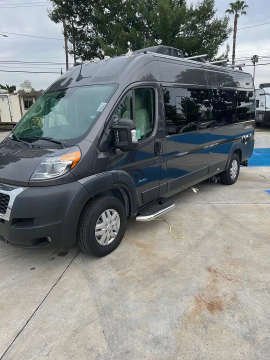 This dark gray Jayco Swift camper van rv rental, with roof racks and step bars, is parked on concrete.. Jayco Swift Li 2023