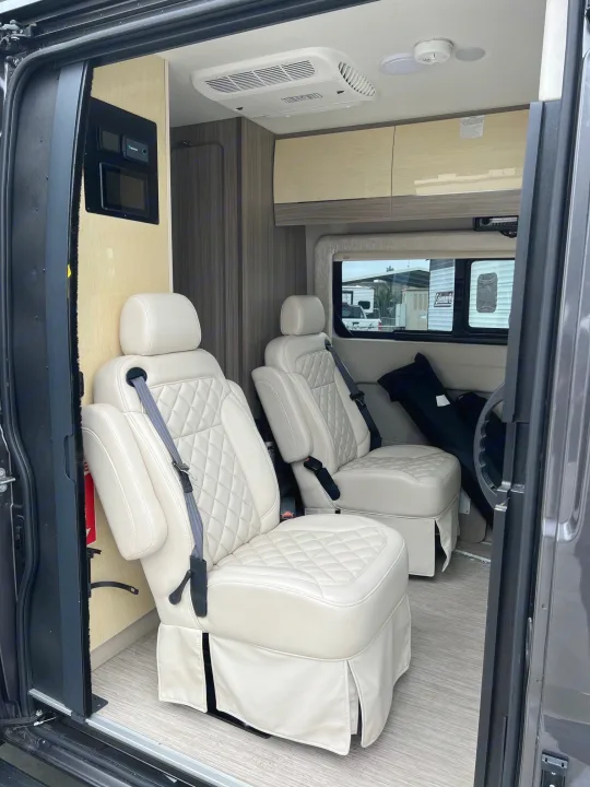 Luxury RV rental interior with cream captain's chairs, control panel, and overhead cabinets.. Jayco Swift Li 2023