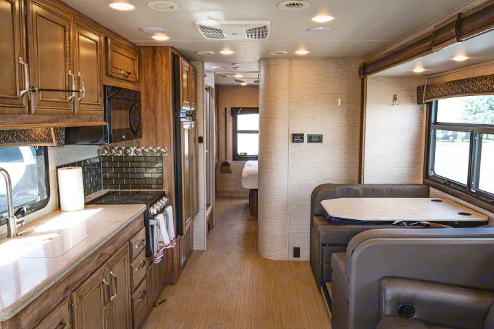 Spacious rv rental interior showing a modern kitchen, dining booth, and a hallway leading to the bedroom area.. Jayco Greyhawk Prestige 2021