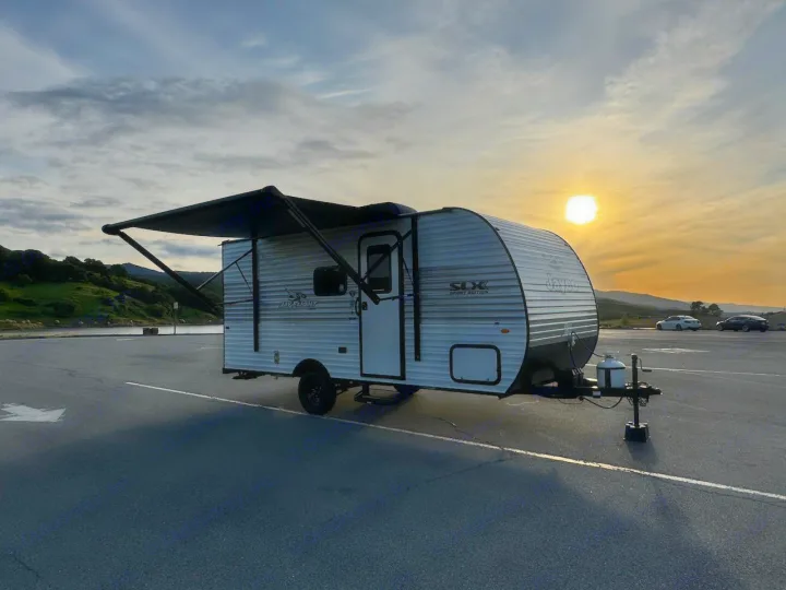 A Jayco travel trailer with awning extended, parked in a lot under a bright sunset sky. Perfect for an RV rental adventure!. Jayco 1UJBC0AJ6F7750334 2026