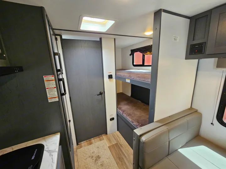 RV rental interior: kitchen with fridge, bunk beds, and dinette. Compact living space for travel adventures.. Keystone RV Bullet Crossfire 2022
