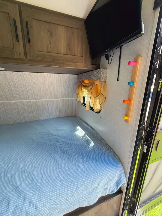 Cozy RV rental interior: bed, cabinets, TV, and a colorful peg rack, perfect for your camper adventure.. Coachmen 17BH 2022