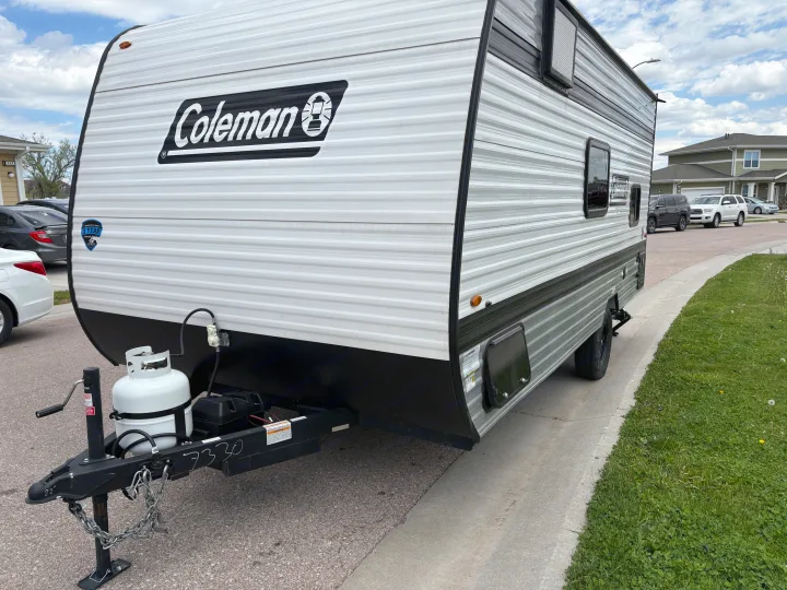 A Coleman travel trailer RV rental, with a visible propane tank and hitch, parked and ready for your next adventure.. Keystone RV Coleman 2025