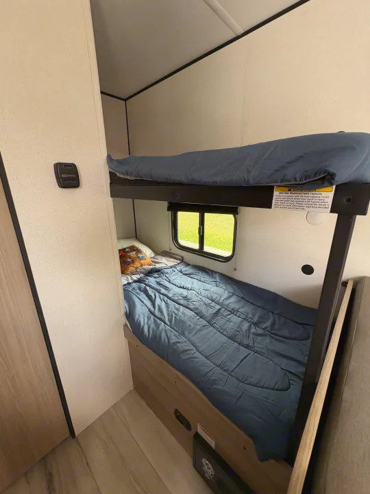 RV rental: Bunk beds inside, with a window and a Suburban thermostat. Top bunk has a 300 lbs max load sticker.. Keystone RV Coleman 2025