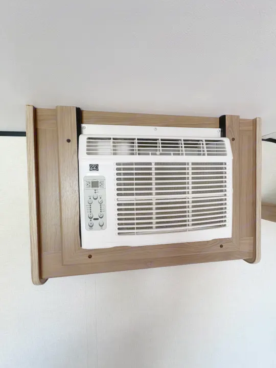 Mounted AC unit with digital and button controls in a wooden frame, installed in an rv rental. Features cooling, fan, and timer settings.. Keystone RV Coleman 2025