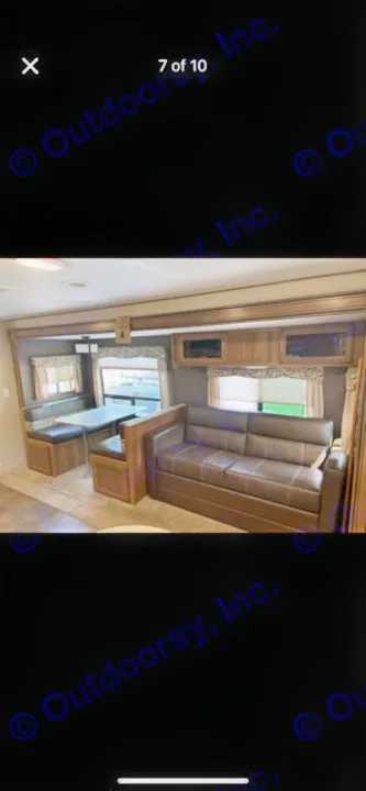 RV rental's inviting interior: a brown sofa, dinette with table, and windows. Ready for your travels.. Coachmen Apex 2017