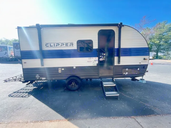 This blue and white Clipper travel trailer RV rental, equipped with steps and a rear rack, is ready for your next adventure.. Coachmen Clipper 2025