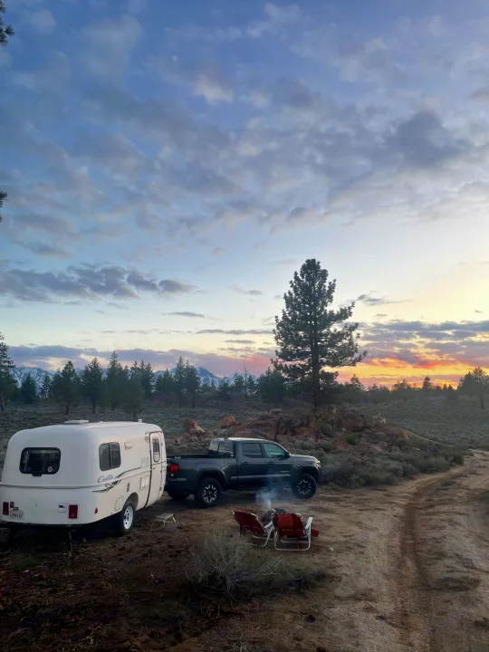 Cozy RV rental setup with a truck, campfire, and mountain views at sunset. Perfect for outdoor adventure.. Casita Casita Trailer 2000