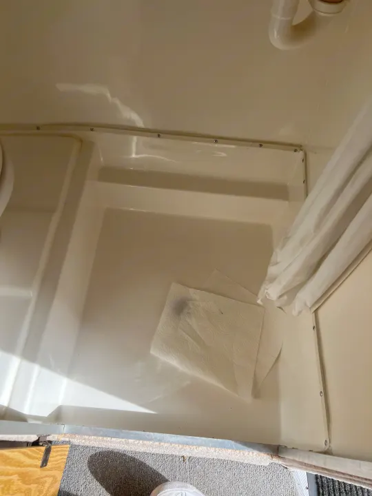 Compact RV rental shower with cream walls, white curtain, and paper towels on the floor. Functional RV bathroom interior.. Casita Casita Trailer 2000