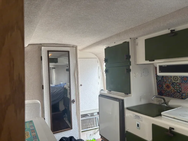 RV rental interior: a compact kitchenette with green cabinets, sink, fridge, and a mirrored door reflecting the sleeping area.. Casita Casita Trailer 2000
