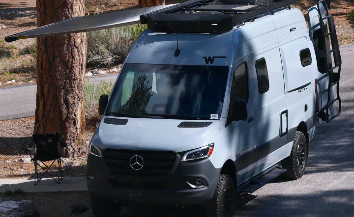 Adventure-ready Mercedes Sprinter rv rental van with awning extended, parked near a tree, ideal for camping.. Mercedes Winnebago 2026