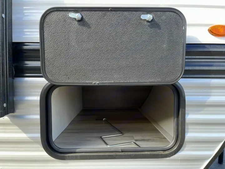RV rental exterior storage compartment, open to reveal ample space and a crank handle, great for gear storage.. Keystone RV Keystone Coleman 13R 2026