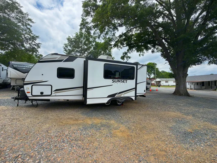 White Sunset Trail travel trailer rv rental on gravel. Ideal for adventures, another RV is nearby.. Crossroads RV Sunset Trail Super Lite 2024