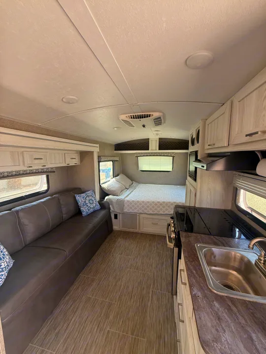 Spacious, modern rv rental interior with a light-toned kitchen, bed, sofa, and wood-look flooring.. Forest River Flagstaff E-Pro 2018