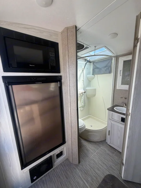 Compact rv rental interior showing microwave, Dometic fridge, and a full wet bath with shower, toilet, and sink.. Forest River Flagstaff E-Pro 2018