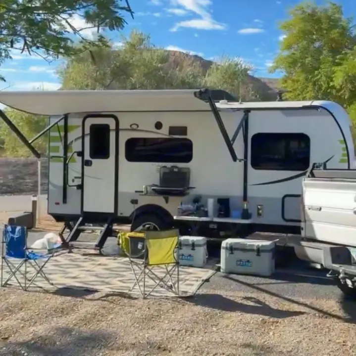 This scenic rv rental camping setup features an extended awning, outdoor kitchen, chairs, and coolers under a blue sky.. Forest River Flagstaff E-Pro 2018