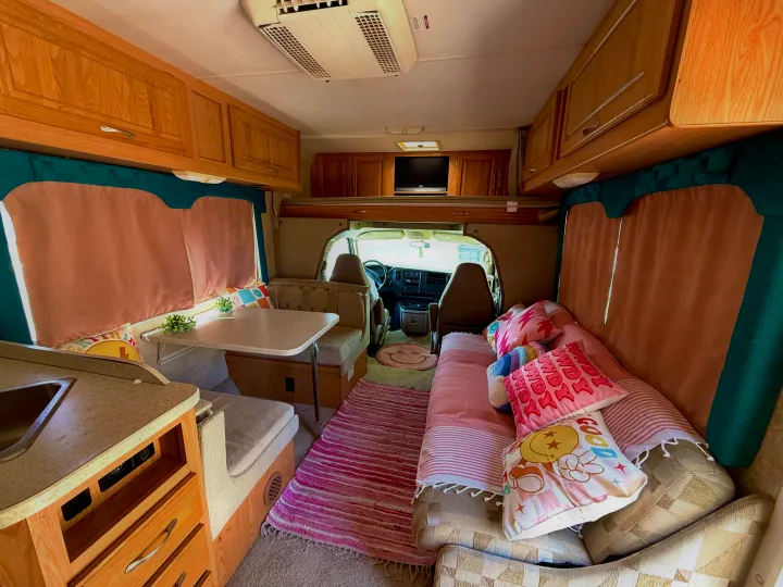 Vibrant rv rental interior featuring a kitchen, dinette, and comfy couch with colorful pillows. Perfect for road trip adventures.. Four Winds 5000 2005
