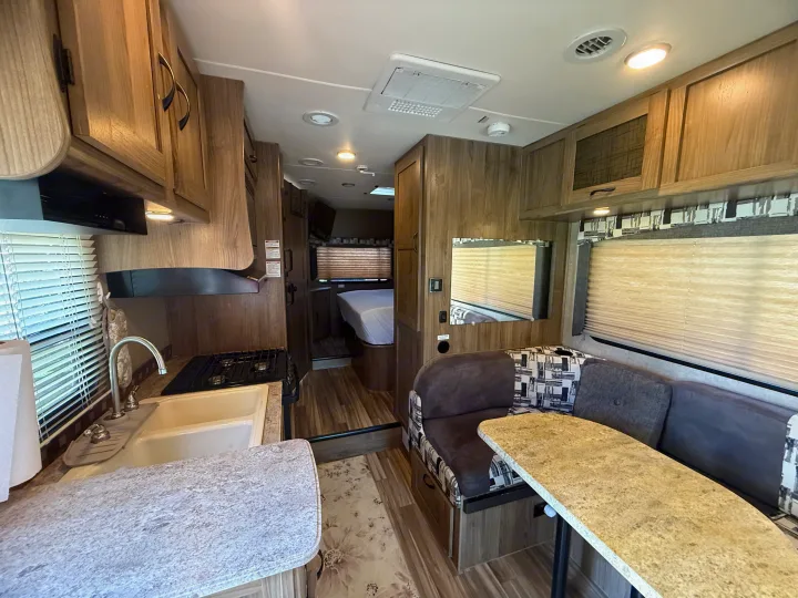 Modern rv rental interior with a functional kitchenette, dining area, and comfy bed visible. Your ideal camper awaits!. Coachmen Freelander 2015