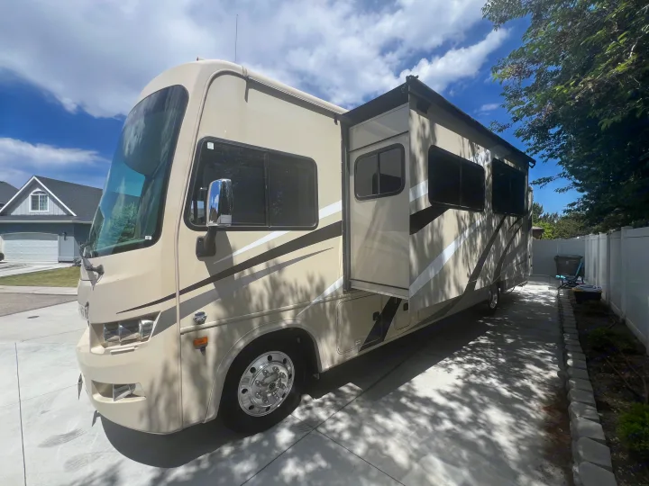 Cream-colored RV rental with extended slide-out, parked on a sunny driveway, ready for your next adventure.. Georgetown GT3 2020