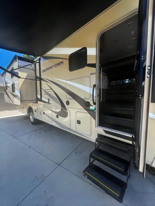 This Georgetown RV rental features an open door with inviting steps, an extended awning, and a slide-out section, parked on a sunny day.. Georgetown GT3 2020