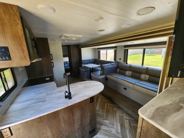 Experience comfort in this rv rental! Modern kitchen, spacious dinette, and cozy U-shaped sofa seating in a bright RV interior.. Forest River Wildwood X-Lite 2021
