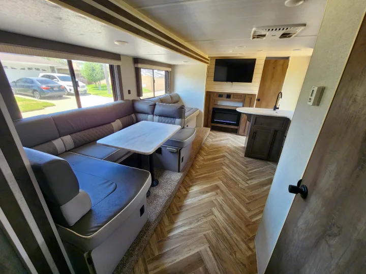 Spacious RV rental interior featuring a U-shaped dinette, modern kitchen, and entertainment center with a fireplace.. Forest River Wildwood X-Lite 2021