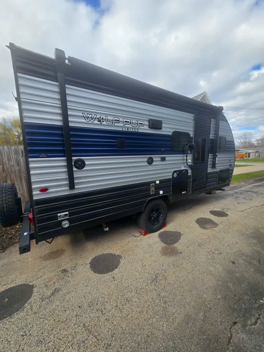 A blue and gray Wolf Pup Limited travel trailer, an excellent rv rental option, is parked on asphalt. Perfect for your next road trip!. Forest River Cherokee Wolf Pup 2022