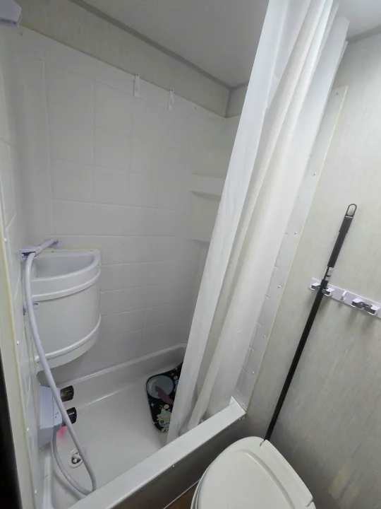 RV rental bathroom featuring a white shower with curtain, compact sink, and toilet, maximizing space for travelers.. Forest River Cherokee Wolf Pup 2022