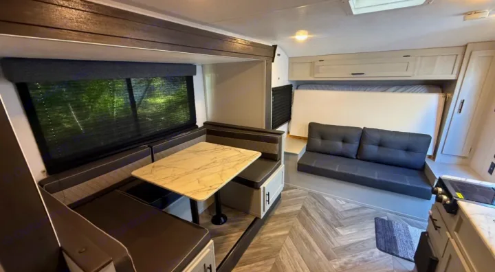 Explore this RV rental's inviting interior: dinette with marbled table, comfy sofa, and compact kitchen.. Forest River Salem FSX 2022