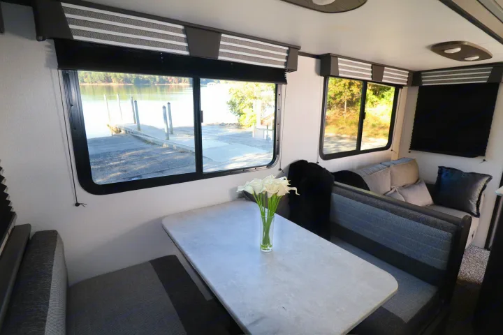 This RV rental interior features a cozy dinette with lake views, perfect for a relaxing travel trailer getaway.. Cruiser RV MPG Ultra Lite 2021